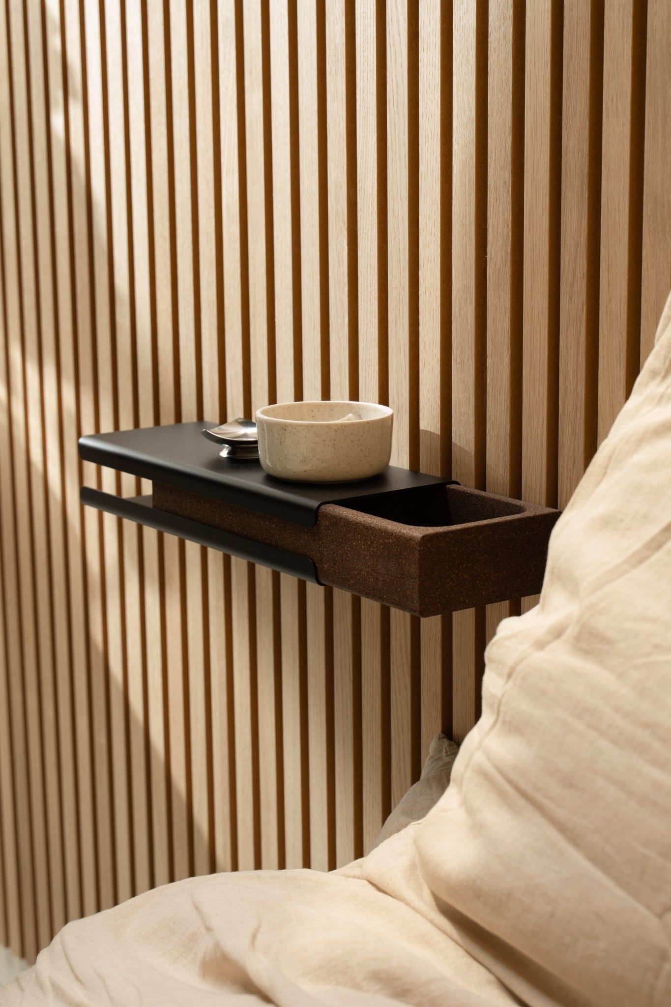 Balda de pared minimalista con un cuenco de cerámica y WoodUpp Norr Key Tray junto a un cojín beige y Akupanel Panel acústico, iluminada por una suave luz natural.